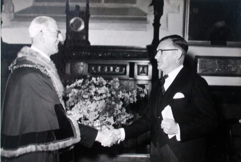 Cecil shakes hands with the new mayor in 1956