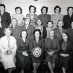Believed to be Launceston WI with Mrs. Slocombe holding the shield (later Mrs. Mounce) to her left is Mrs Stanbury, Vera Gilbert top left, and Mrs Raymont is third from the right at the back. Photo courtesy of Peter Gilbert.